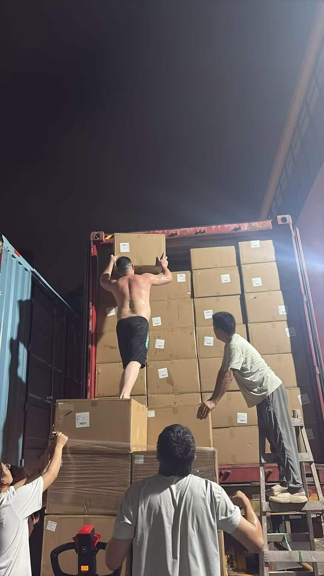 Tim memuat karton ke dalam kontainer pada malam hari