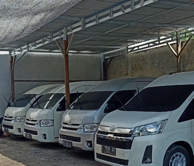 Van Toyota HiAce putih di bawah kanopi pool kendaraan